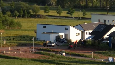 Man driving a small red shovel excavator outside homes, rural Germany, work Stock Footage 89556464