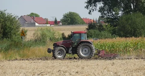 Man is Driving The Tractor on The Field With Plow is Plowing The Soil Houses Stock Footage 53608408