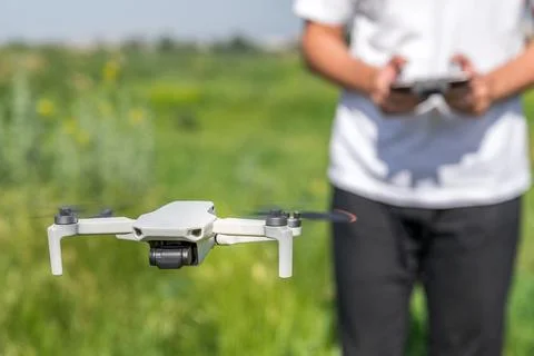 A man a drone pilot with a control panel in his hands controls a quadcopter in Stock Photos
