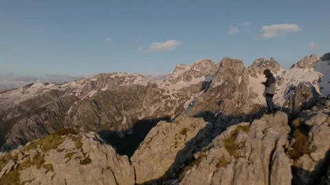 Man drone pilot on the mountain summit - huge mountain peaks on sunset light Stock Footage 250000221