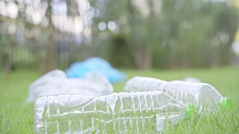 A man dropped a plastic bottle on the grass in a park. He destroys nature and in Stock Footage 145177311