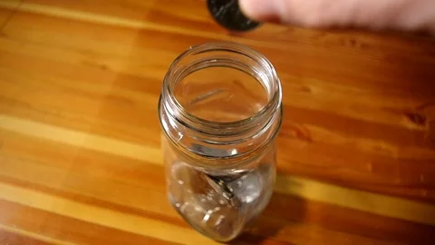 A man dropping a coin into a jar. Stock Footage 106918317