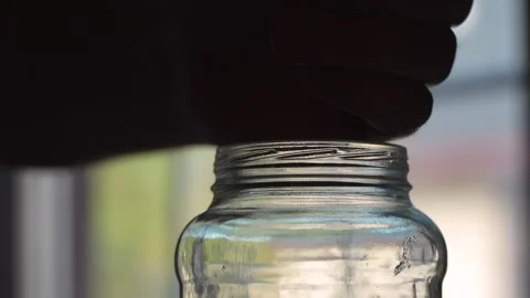 Man dropping coins into a large glass jar 스톡 동영상 320189979