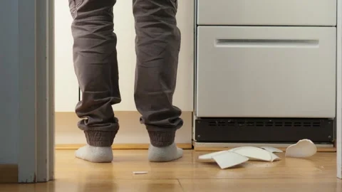 Man dropping a plate on kitchen floor. Shattering into pieces. Slow motion Видео 332678417