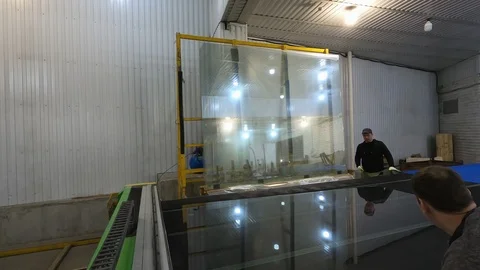 The man drops the glass sheet from the rack on the table for overcutting. 스톡 동영상 124275277