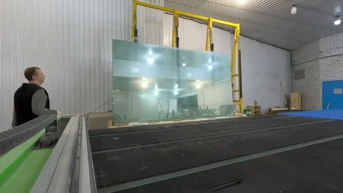 The man drops the glass sheet from the rack on the table for overcutting. Stock Footage 125264268