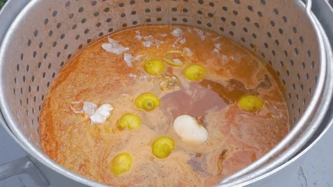 Man Drops Onions into a Large Pot of Spicy Cajun Broth at a Crawfish Boil Stock Footage 74971828