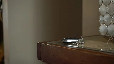 A man drops then grabs his car keys off a table at home Stock Footage 194513078