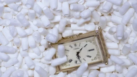 Man drops watch into a box of soft filler and foam sticks in slow motion. Stock Footage 197571374