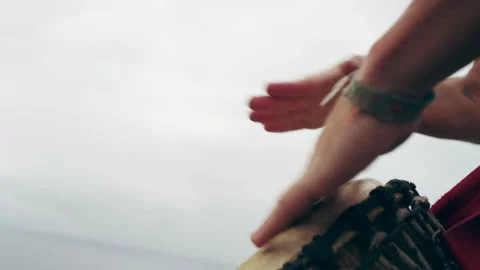 Man drumming on Djembe drums by the ocean Stock Footage 279059019