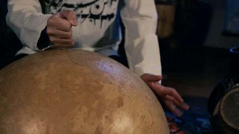 Man drumming out a beat on an arabic percussion drum named Calabasse at home. Stock Footage 74519480