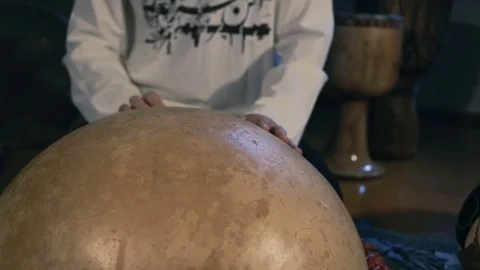 Man drumming out a beat on an arabic percussion drum named Calabasse at home. Stockbeeldmateriaal 74519662