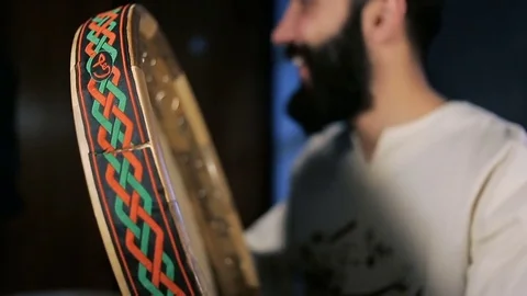 Man drumming out a beat on an arabic percussion drum named Dayereh at home. Stockbeeldmateriaal 74526562