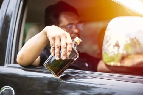 Man drunk during drive a car. driver with alcohol whisky bottle dangerous and Stock Photos