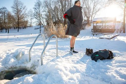 Man drying off  after cold winter swimming in the golden sunlight of a snow.. Stock Photos