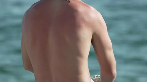 Man drying back with towel on sunny beach after refreshing swim Video stock 312872269