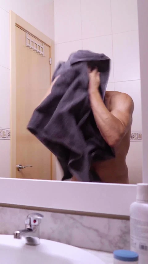 Man drying himself with towel in bathroom mirror Stock Footage 313429934