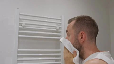 Man drying his face with a towel in the bathroom Stock Footage 340430736