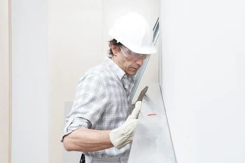 Man drywall worker or plasterer checking level of white plasterboard wall wit Stock Photos