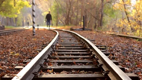 A man with DSLR camera walks down train tracks on a background Autumn forest. A Stock Footage 83334417