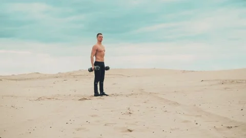 Man with dumbbells in desert Видео 90486796