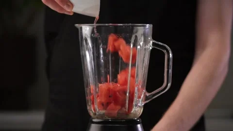 A man dumps a watermelon into a blender. Making smoothies in a blender. Healthy Stock Footage 219564511