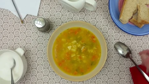 Man dunking bread in a bowl of vegetable soup Stock Footage 78077507