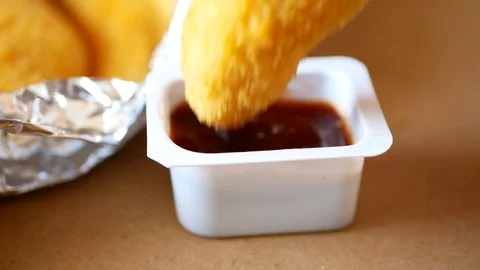 Man dunks a piece of chicken strip in the sauce. Stock Footage 70403702