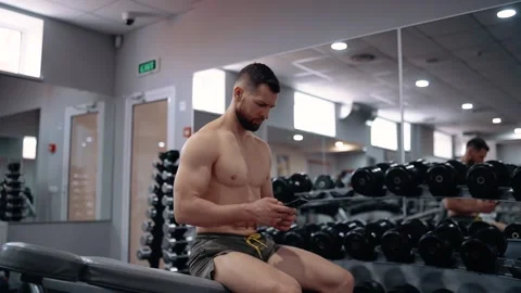 The man, during the break between exercises, looks on the phone. Intensive Video stock 156867475