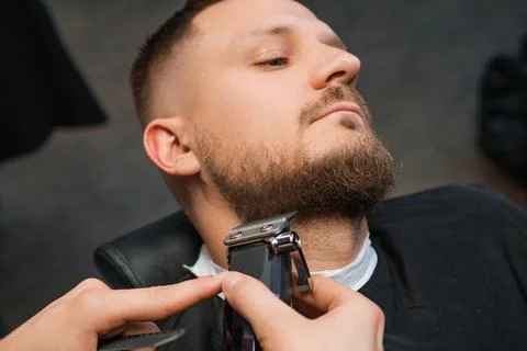 Man during the procedure of cutting beard. Stock Photos