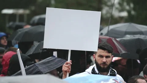 Man during rain with empty mockup advertisement poster panel for advert logo. Video stock 164885098