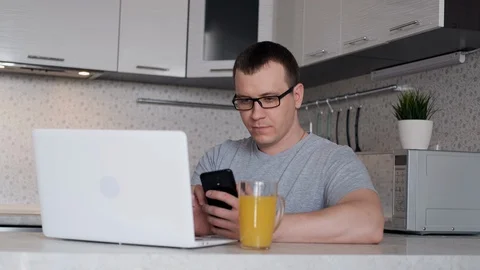 A man during remote work from home writes data from a phone to a laptop while Stock Footage 127586985
