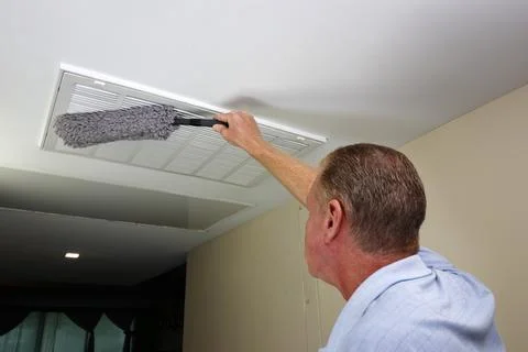 Man Dusting with a Dust Wand a Ceiling Furnace Air Intake Vent Grid Stock Photos
