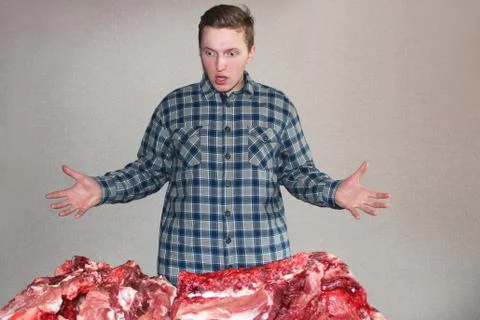 A man eagerly looks at raw meat. A lot of fresh meat. Man and raw meat Foto stock