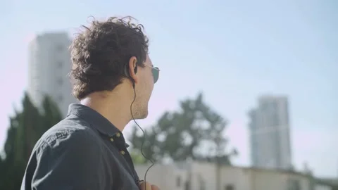Man with ear piece talking - during a covert mission lookout from city building Stock Footage 131279032