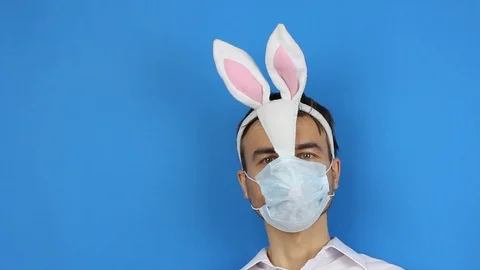 Man in easter bunny and medical mask smile and looks around, twirls his eyeballs Stock-Footage 126998904