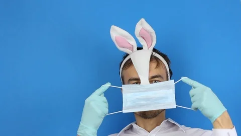 Man in easter bunny mask and protect gloves puts on medical mask and thumb up Видео 126998896