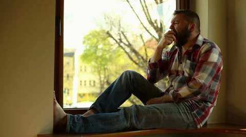 Man eat apple, sitting on windowsill Video stock 62824474