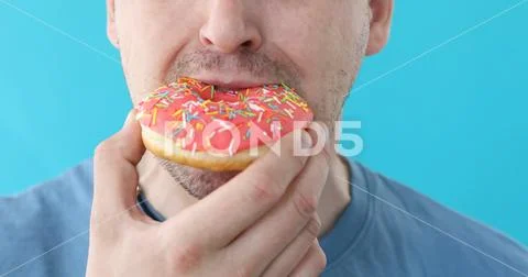 Man eat donut closeup on a blue background Stock Photos