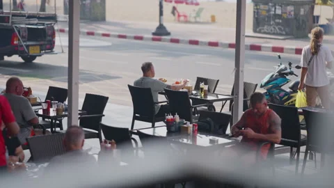 Man Eating Alone at Seaside Restaurant with Busy Traffic Stock Footage 337533950