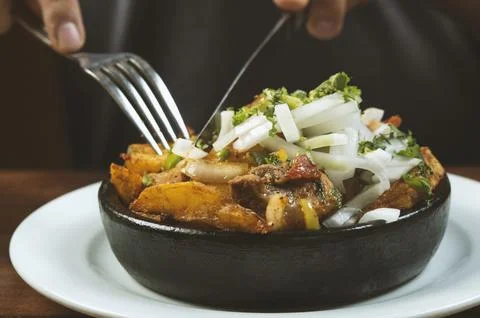 Man eating Beef stew with potatoes, carrots and herbs on black background wit Stock Photos