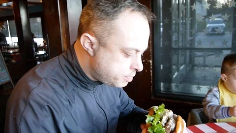 Man eating biting a big beef hamburger burger at the fast food restaurant Stock Footage 91755418