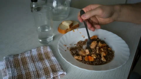 Man eating buckwheat, chicken, bread and drinking water at home, plate closeup. Stock Footage 152531356
