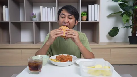 A man is eating a burger and drinking a soda Stock Footage 314874223