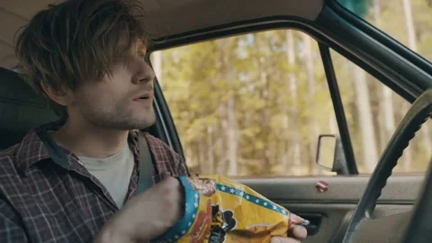 Man eating cheese balls while carelessly driving and crashes Stock Footage 83223681