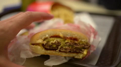 Man eating cheeseburger at a table fast-food cafe McDonald's Stock-Footage 64081244