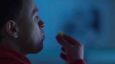 Man eating chips and watching TV in the evening light, the reflection Stock Footage 155174366