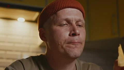 Man eating chips in warm evening light of kitchen Stock-Footage 320137856