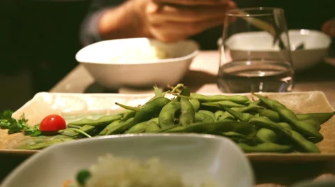 Man eating eda mame, a typical japanese food, beans rich in protein and rice Stock-Footage 56089026