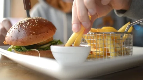 A Man eating French fries with Tomato Ketchup and Burger with Greens and Shrimp Stock Footage